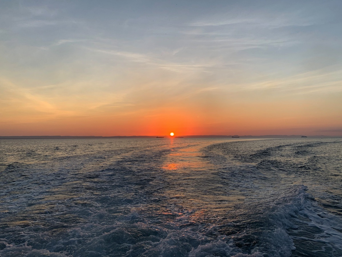 Imagen de un atardecer sobre el océano con tonos naranjas y morados